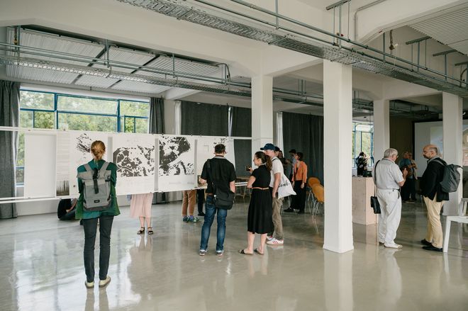 Besuchende in der Ausstellung vor großformatigen Plänen