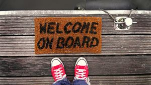 Photo: Mabel Amber; Source: Pexels  Two feet in front of a fum mat with the imprint »Welcome on Board«.