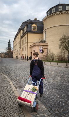 Larissa Barth (Vordergrund) transportiert ihre Gedenktafel für Herzogin Anna Amalia von Sachsen-Weimar-Eisenach mit der Sackkarre zur Herzogin-Anna-Amalia-Bibliothek Weimar (Hintergrund).