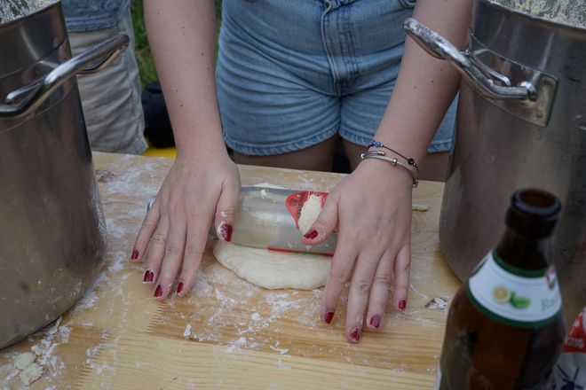 Instead of a rolling pin, a glass bottle is used to roll out pizza dough.
