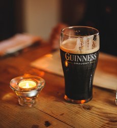 The photo shows a full pint glass and a tea light on a pub table.
