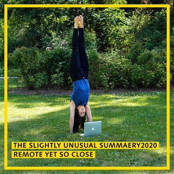 a woman does a handstand while looking at a laptop screen