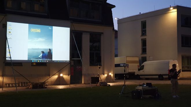 The event starts. Dr. Michael Wallner welcomes the guests on the lawn in front of the Van de Velde building. Behind him is the screen.