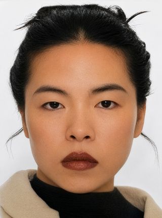 Photo: Mai Do Portrait of Mai Do. She faces the camera wearing a light-coloured coat over a black top. Her dark hair is tied up.