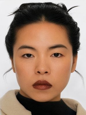 Portrait of Mai Do. She faces the camera wearing a light-coloured coat over a black top. Her dark hair is tied up.