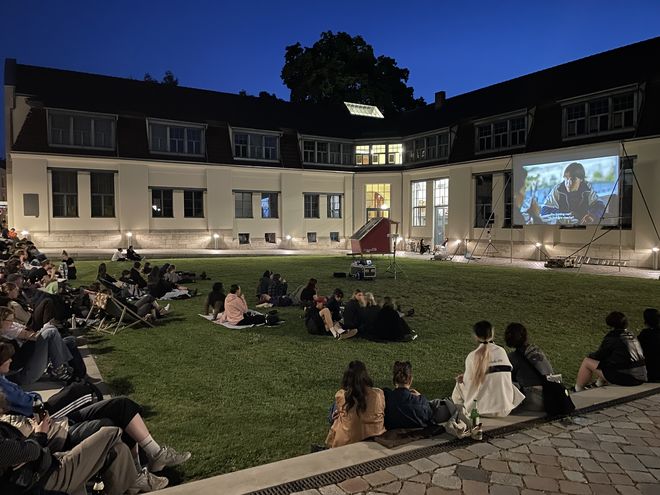Photo taken during the screening. It shows the guests on the lawn in front of the Van de Velde Building and the screen.