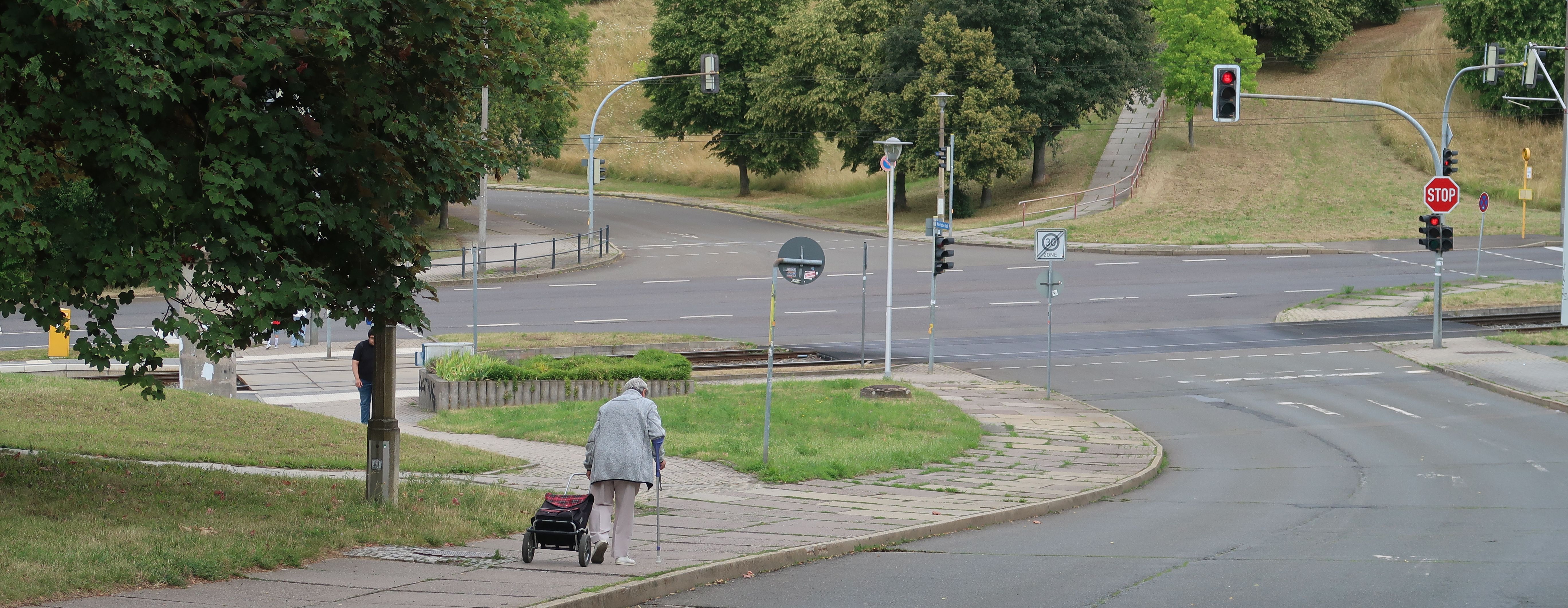 Blick auf eine gewundene Straße in Bieblach-Ost (Gera), eine Person läuft am Gehweg entlang