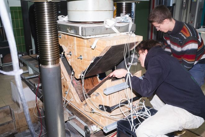 Julian Linden und Linus Enzmann in einer Werkstatt beim Verformen eines großen Stückes des Materials