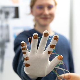 Ein Handschuh, der die Beweglichkeit des Daumens testet: Elina Grüning präsentiert »RhiTech«. Gemeinsam mit Kim Dufft und Lara Ostrowski belegten die Schülerinnen den 1. Platz bei »Jugend forscht« im Bereich Arbeitswelt. Foto: Bauhaus-Universität Weimar/ Matthias Eckert 