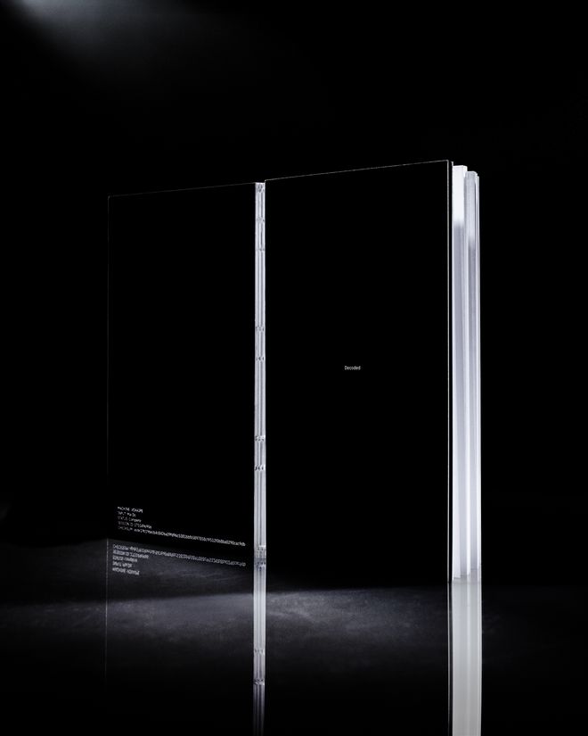 Aufgeklapptes Booklet mit schwarzem Umschlag. Links maschinelle Textausgaben wie »Machine: VOXAIPE«, rechts der Titel »Decoded«.