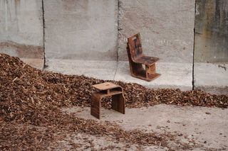 zwei fertige Sitzmöbel neben einem großen Haufen von Häkseln aus Rinde