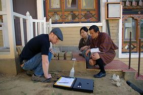 Dipl.-Ing. Christoph Kulle mit den Gästen Jamyang Dukjey und Karma Euthra in den Laboren der Professur Bauchemie und Polymere Werkstoffe bei der Untersuchung der kapillaren Wasseraufnahme von zementstabilisierten Lehmsteinen, Foto: Karma Tenzin
Dipl.-Ing. Christoph Kulle mit den Gästen Jamyang Dukjey und Karma Euthra in den Laboren der Professur Bauchemie und Polymere Werkstoffe bei der Untersuchung der kapillaren Wasseraufnahme von zementstabilisierten Lehmsteinen, Foto: Karma Tenzin