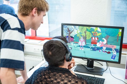 Die Bauhaus-Universität Weimar auf der Leipziger Buchmesse 2024 Zwei Personen schauen auf einen Bildschirm, auf dem ein Computerspiel läuft