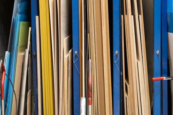 Vertically stored wooden boards and wood-based materials in various thicknesses and colors arranged in a rack.