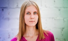 The colored portrait photo shows Galyna Sukhomud from the shoulders up. She has smooth, blond, shoulder-long hair and green-grey eyes. She is wearing a raspberry-red top with a geometrical pattern of white lines.