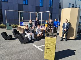 Der Stresstest beim Probeaufbau vor der Holzwerkstatt der Fakultät ist bestanden. Foto: Florian Hesselbarth Studentisches Team im Freien vor Teilen des noch nicht fertigen Messestandes