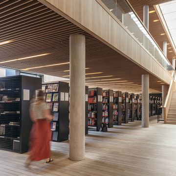 Bücherreihen in der Bibliothek, eine Frau läuft vorbei