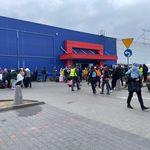 Menschen mit Kindern auf den Armen vor einem Logistikzentrum.