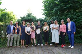 Group photo outdoors in front of a green hedge