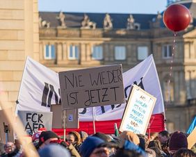 Plakate auf einer Demo (Copyright: Alex Fremer, CC BY-SA 2.0 <https://creativecommons.org/licenses/by-sa/2.0>, via Wikimedia Commons)