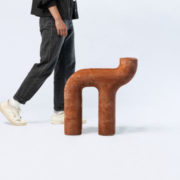 Foto des Sitzmöbels; im Anschnitt die Beine einer Person, die vorbei läuft.