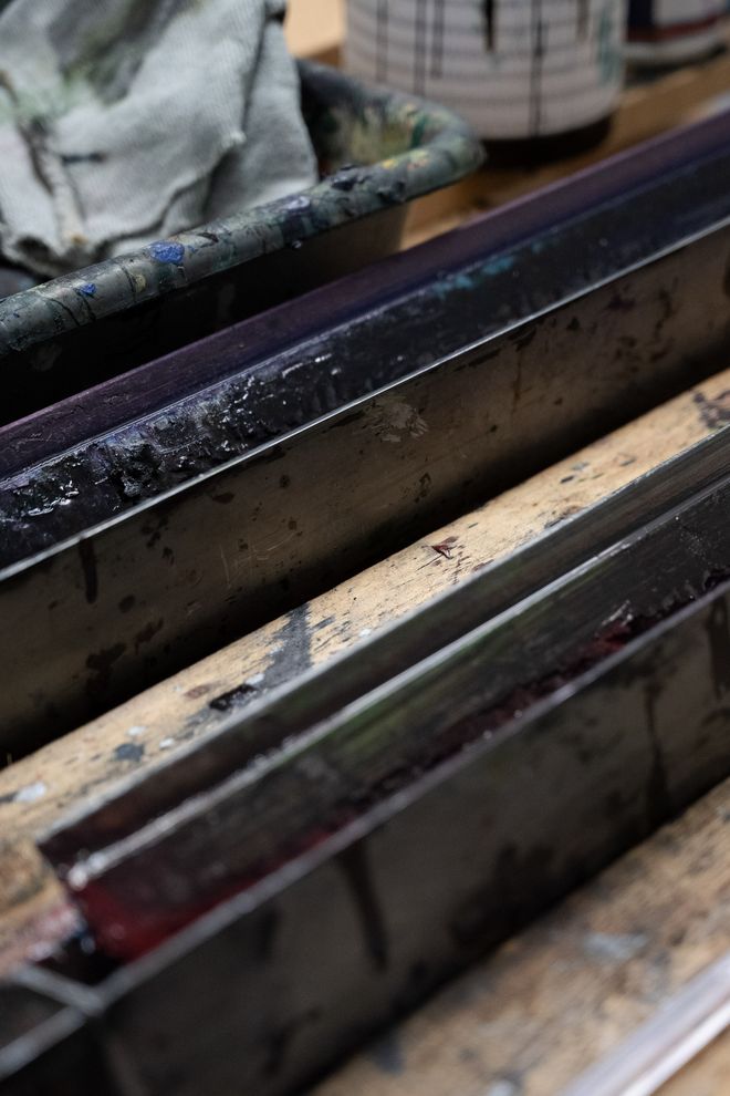 Nahaufnahme von mit Farbe verschmierten Rakeln in einer Wanne, Detail der Druckwerkzeuge.