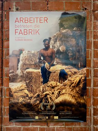 Filmplakat zu »Arbeiter betreten die Fabrik« von Florian Wehking, zeigt einen Arbeiter bei der Verarbeitung von Pflanzenfasern in einer Fabrikumgebung.