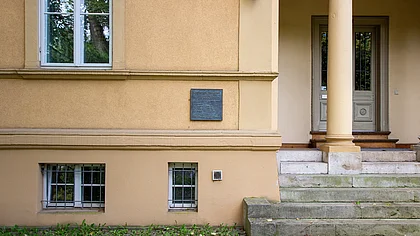 Ansicht einer Eingangssituation eines Hauses. Links der durch eine Stütze gegliederten Eingangssituation befindet sich eine Bronzetafel mit der Inschrift: Ghettohaus 1940 – 1942 1900 Wohnhaus des Ehepaares Friedrich Fleischer, Kunstschulprofessor Jenny-Fleischer-Alt, Kammersängerin 1940/41 Zwangseinweisung jüdischer Bürger Zum Gedenken an: Jenny Fleischer-Alt Freitod 1942 Edith Gál Freitod 1942 Ilka Gál Tod 1942 Käthe Friedländer Deportation 1942 verschollen Martha Kreiss Tod 1944 Eduard Rosé, Deportation 1942 Cellist, Konzertmeister Tod 1943 in Theresienstadt
