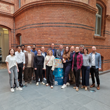 Eine Gruppe von Personen steht vor einer Ziegelwand