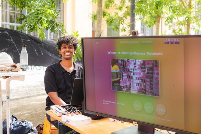 eine Person sitzt am Rechner der summaery-Fotobox und lacht in die Kamera