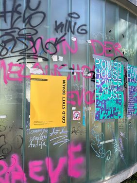Foto: Marit Haferkamp Plakat der Aktion »Gold statt Braun« an einer mit Graffiti besprühten Glaswand
