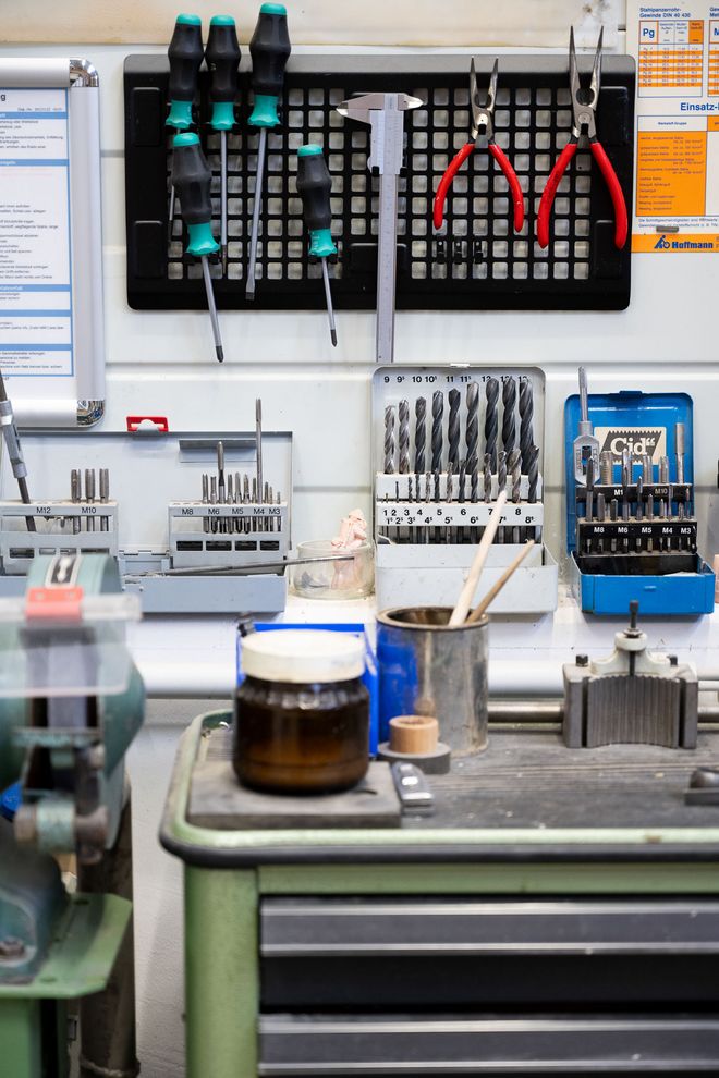 Wandmontiertes Ordnungssystem mit Schraubendrehern, Zangen, Messschiebern und sortierten Bohrern in einer Werkstatt.