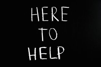 Auf einer Tafel steht geschrieben »Here to Help«