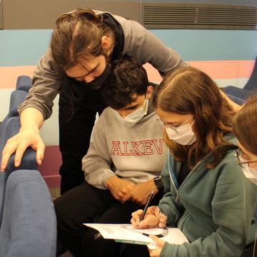 Drei Schlüer*innen beugen sich über ein Dokument, in welchem sie intensiv lesen. Foto: Bauhaus-Universität Weimar, Serap Resimcioğlu