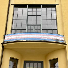 Banner in the colors of the Trans Pride flag on the balcony of the Main Building.