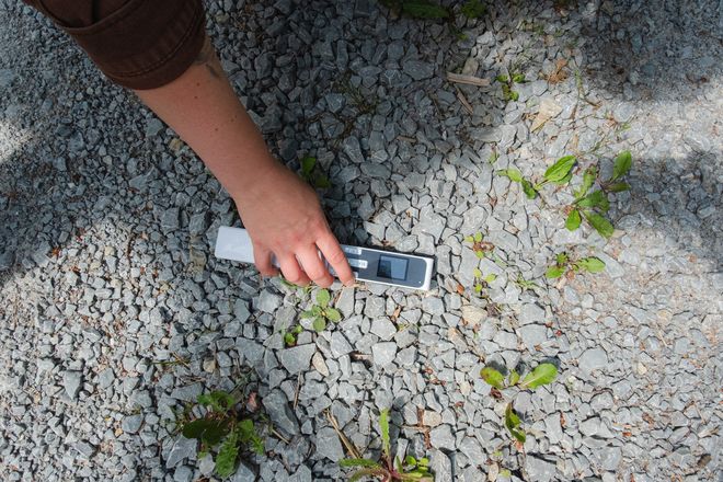 eine Person, die ein Messgerät auf den Schotterboden hält
