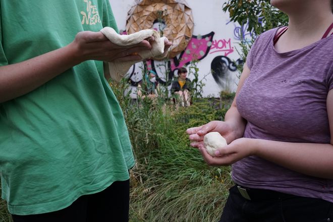 Two people kneading dough in their hands.