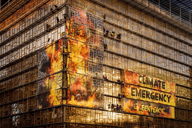 Greenpeace activists wrap the EU summit venue in Brussels with images of giant flames, setting off clouds of smoke, flares and sounding a fire alarm to urge European government leaders to take immediate action to respond to the climate emergency.