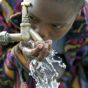 Ein südafrikanischer Junge trinkt Wasser aus einem Wasserhahn