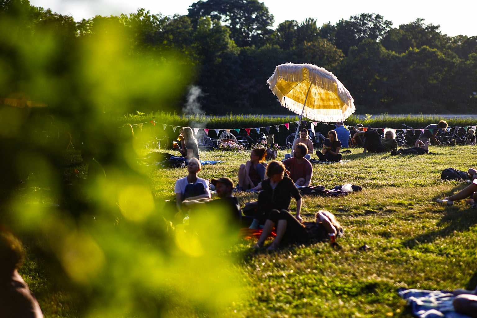 Scene from the radio play summer: Meadow with people and yellow parasol in the evening sun; Photo: Tino Pfund
