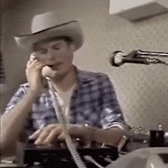 Piratensender-Moderator mit einem Cowboyhut und einem Telefonhörer in der Hand.